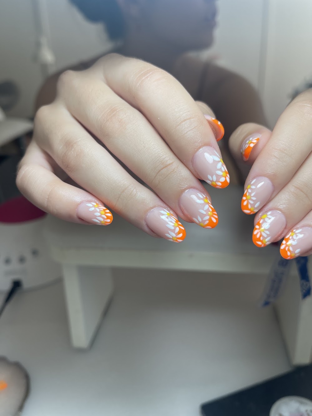 Uñas con puntas naranjas y flores blancas tipo margarita