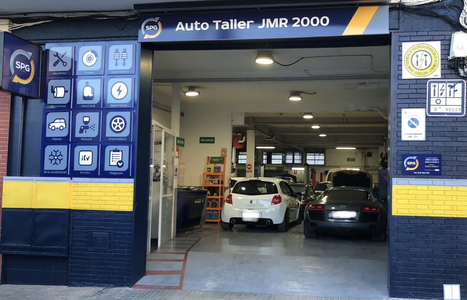 Fachada de Autotaller JMR 2000 en Sant Pere de Ribes, con el panel de servicios y coches en el taller
