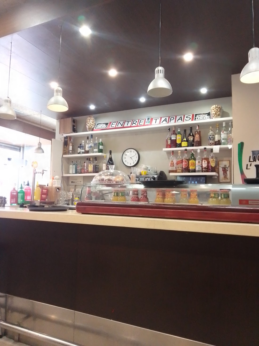 Barra de Entre Tapas con el rótulo del local, botellas y cafetera