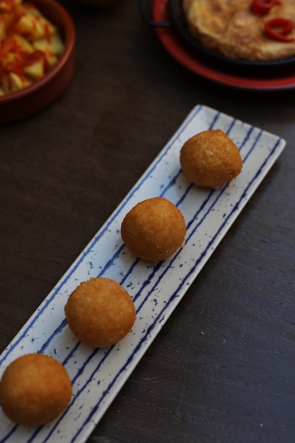 Croquetas caseras doradas sobre plato de rayas