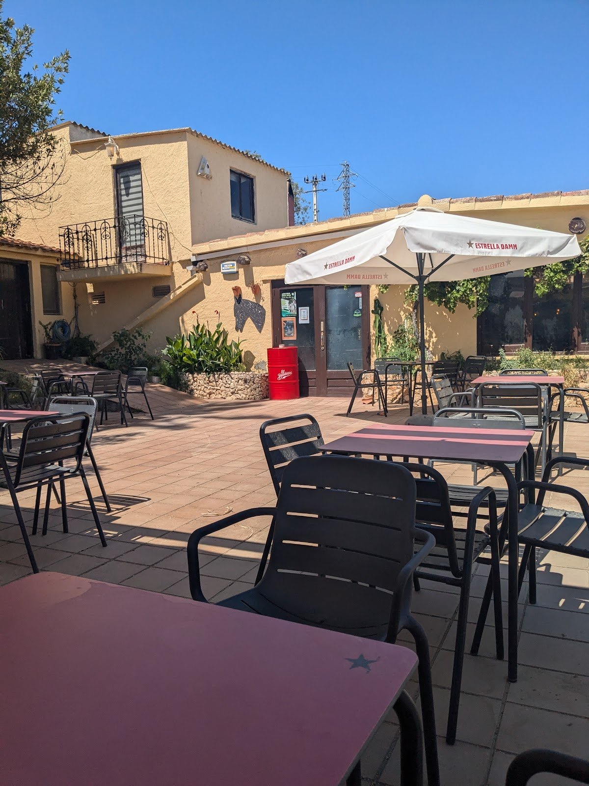 Terraza exterior de La Serreta en la masía, con sombrilla y sillas