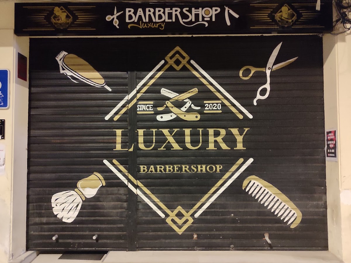 Fachada de Luxury BarberShop con el rótulo dorado sobre fondo negro y el emblema con navajas